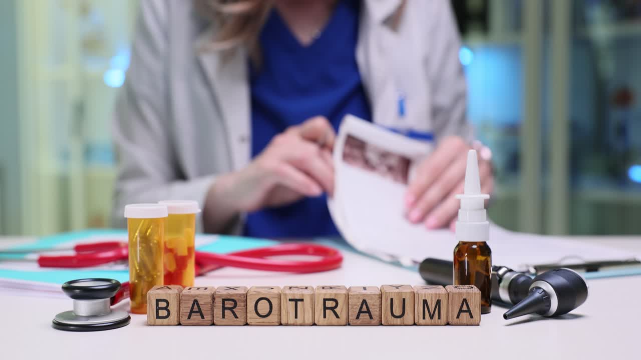 Cubetti di legno che formano la parola "barotrauma" su una scrivania medica, accanto a un medico.