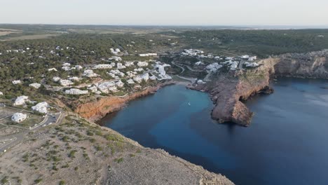 Drone-parallax-of-Cala-Morell-coastal-town-at-mid-morning,-calm-serene-scene