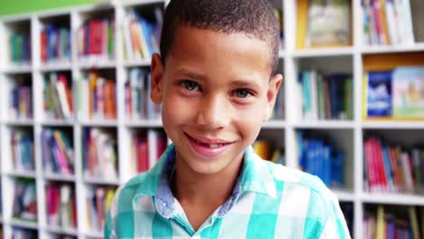 Portrait-of-schoolboy-smiling-in-library-at-school