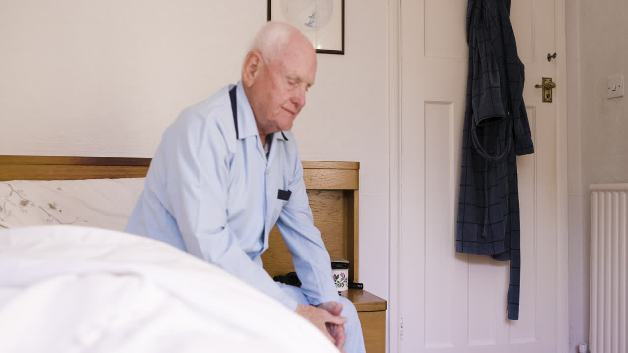 An elderly man sitting on a bed