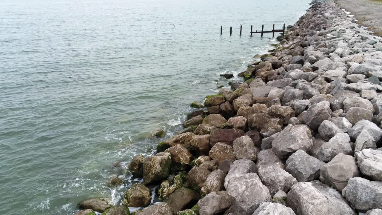 vista aérea hacia adelante después de la salpicadura de la marea del océano rompiendo en la costa rocosa
