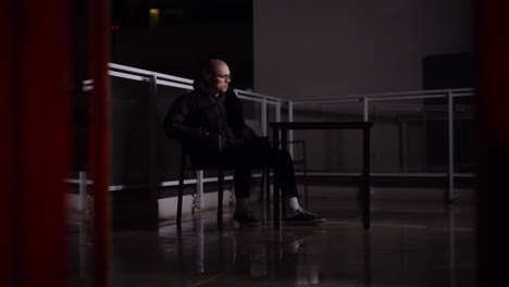 man sitting on a balcony at night using a smartphone