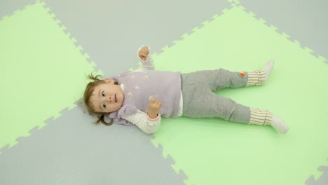 Top-view-of-tired-little-girl-with-pigtails-lying-on-a-floor-relaxing-after-playtime