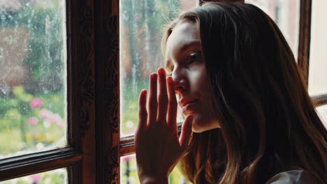 una chica mirando por una ventana antigua.
