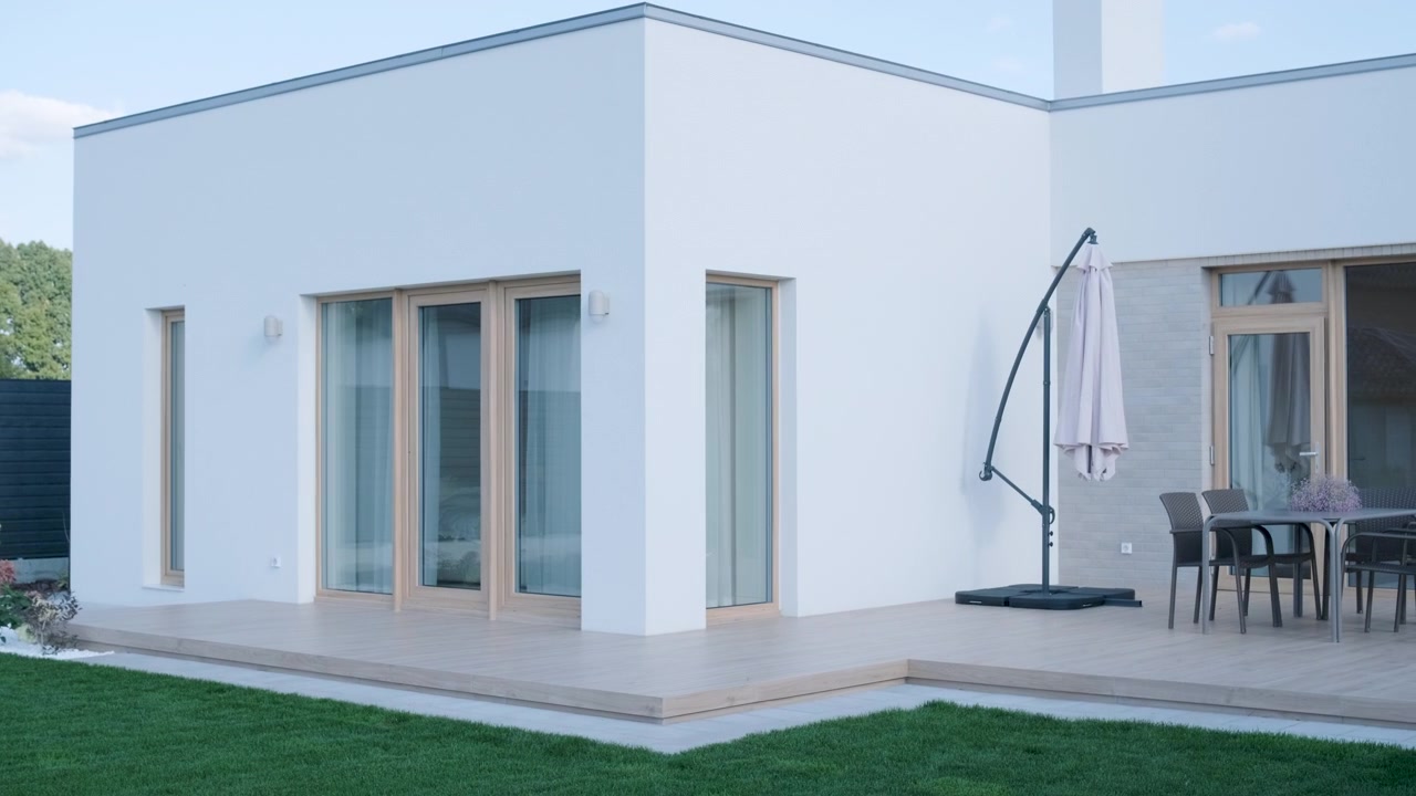 Esterno di una casa bianca moderna con terrazza in legno e mobili da giardino