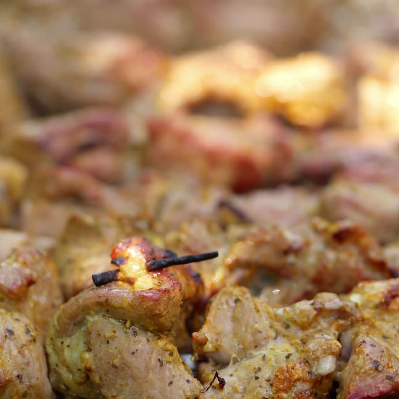 Barbecue in smoke. Meat on skewers cooking on the grill. Pork meat on the mangal in nature. Tasty shashlik cooking on the coals. Close-up.