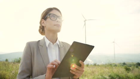 zbliżenie kaukaskiej kobiety-inżyniera używającej tabletu na stacji wiatrowej energii odnawialnej