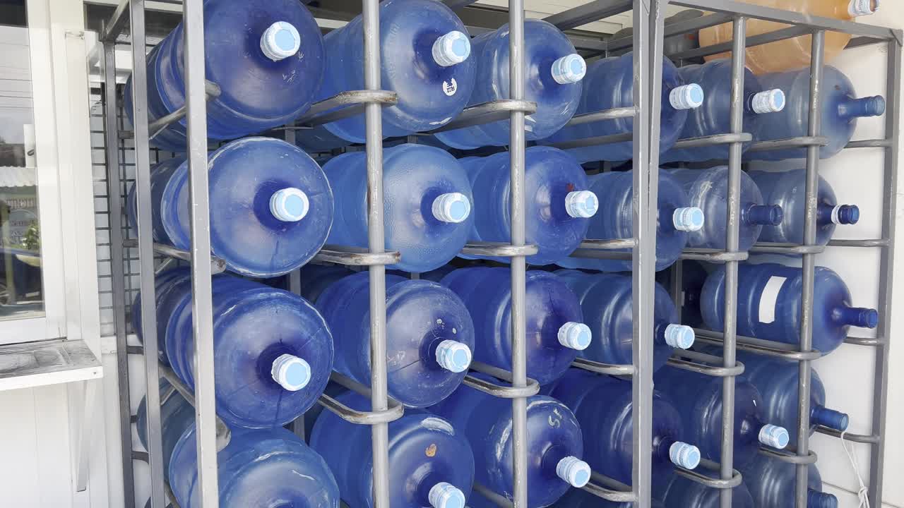 Blue plastic water bottles organized in a metal storage rack under daylight conditions