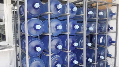 blue plastic water bottles organized in a metal storage rack under daylight conditions