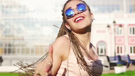 young beautiful girl with dreads dancing in a park. beautiful woman in jeans and sunglasses listening to music and dancing