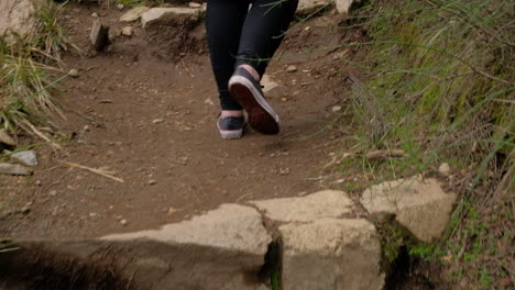 young girl legs in sneakers walking on a path climbing some stone steps