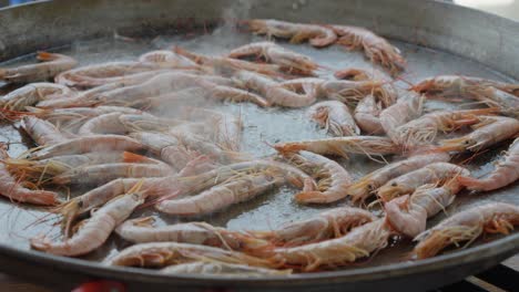 slow orbiting shot of a large pan of shrimp being cooked to be served