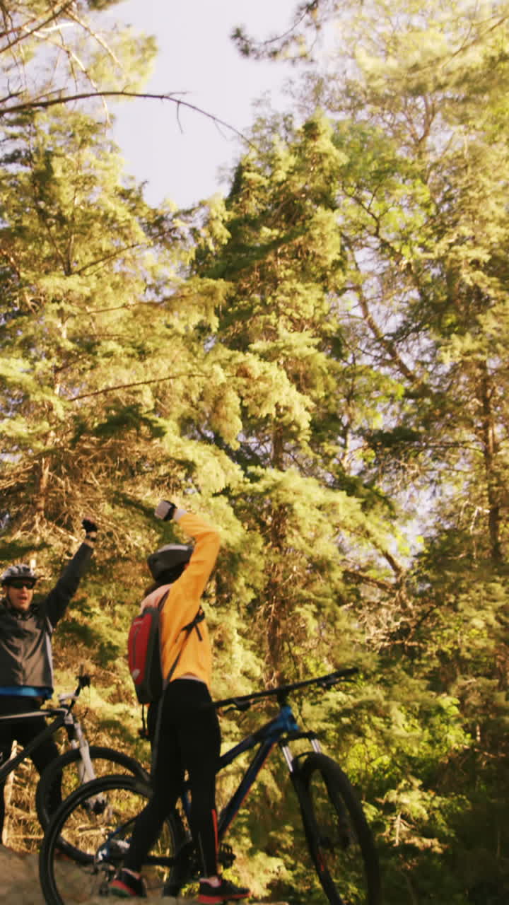 Casal de ciclistas de mountain bike entusiasmado em pé sobre uma rocha