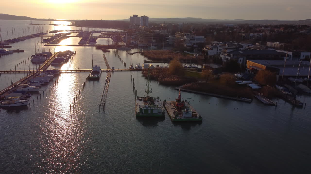 Drone sunset view of Balatonfured harbor with boats docked and golden reflections on water