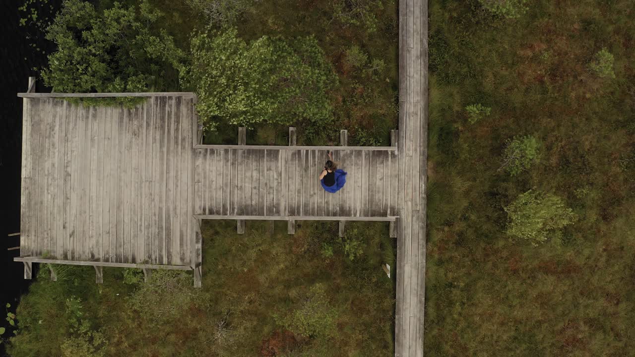 바람 부는 날씨에 사진을 찍고 인 도교를 떠나는 여자 위