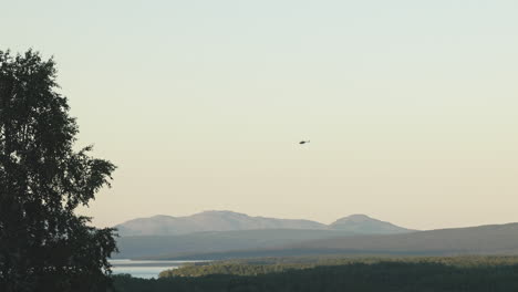 helicopter-flying-over-the-mountainous-area-of-Klimpfjall,-north-of-Sweden,-at-dusk