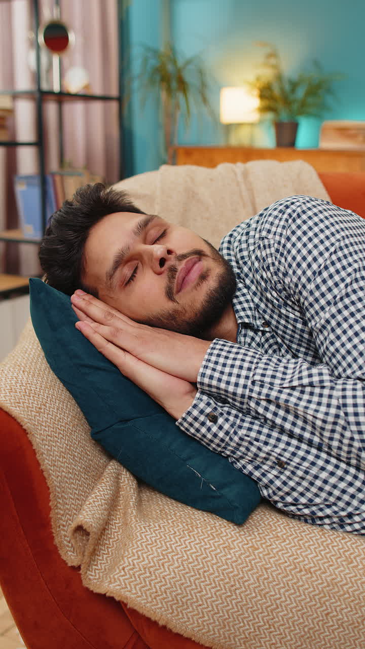 joven indio cansado acostado en la cama tomando un descanso en casa durmiendo durmiendo en el sofá