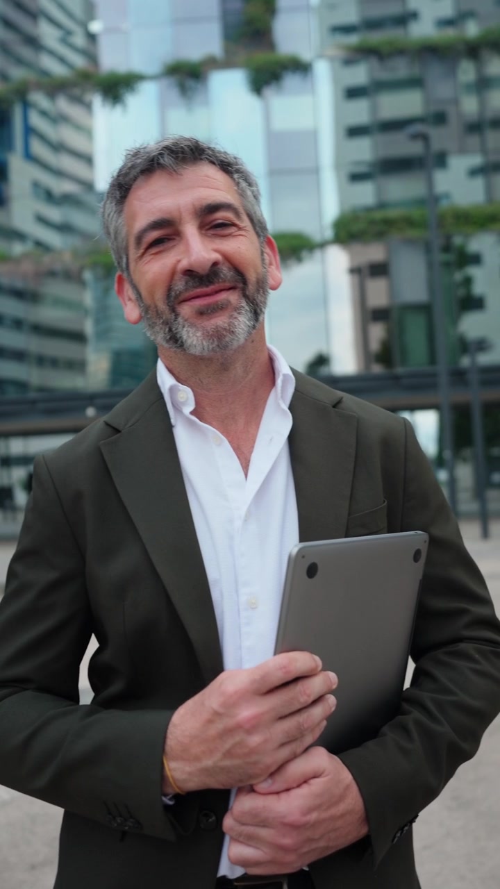 Empresário maduro fechando o laptop e sorrindo em um ambiente urbano moderno
