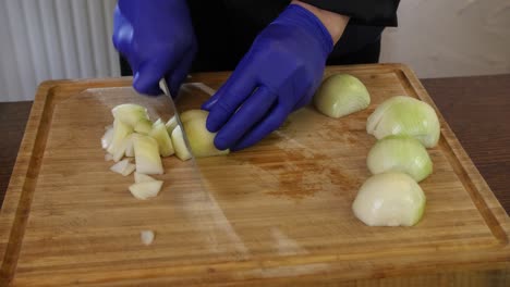 Cerrar-Los-Jefes-De-Chef-Profesionales-Con-Guantes-Para-Picar-Cebolla-En-Una-Tabla-De-Cortar-De-Madera-En-La-Preparación-De-Alimentos-De-La-Cocina-De-Un-Restaurante-Profesional