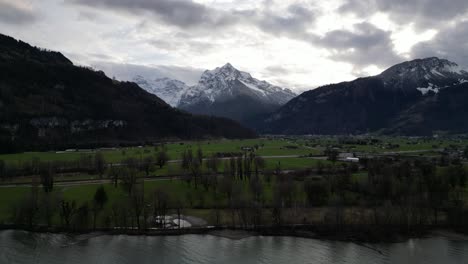 Late-afternoon-light-pierces-cloudy-sky-illuminated-mountain-peak-in-distance-with-grassy-fields-and-light-traffic