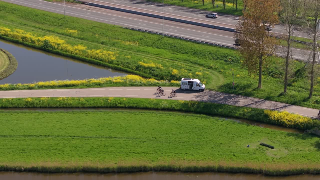 オランダの田園地帯にある曲がりくねった道を疾走するサイクリストの空撮。