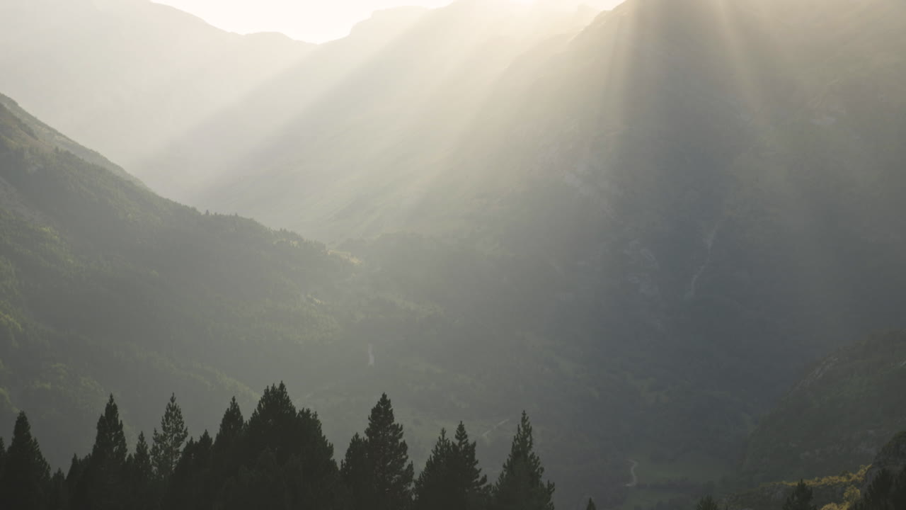 Sunset run says through the mountains in Benasque Mountain, Spain, wide tilt up