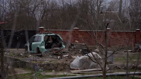 A-rusty-abandoned-car-in-the-parking-lot,-surrounded-by-a-fence-and-barbed-wire.-A-couple-of-cars-are-standing-in-a-sump-for-automotive-disassembly-or-metal-processing.-Restoration-of-a-retro-car.