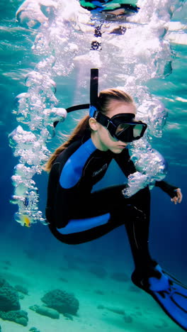 young person snorkeling underwater amidst bubbles and fish