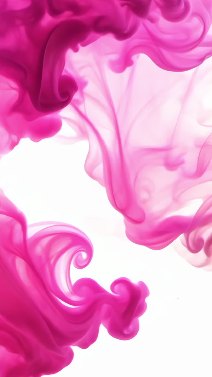 Colorful Pink Ink Swirls Across White Background Creating Abstract Art. Dynamic pink ink swirls blend and disperse artistically against a white backdrop. Vertical video