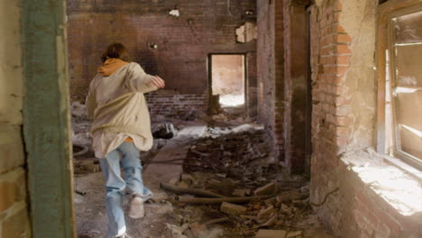 vista trasera de una chica pelirroja huyendo en un edificio en ruinas