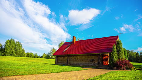 Rustikale-Schönheit:-Bezaubernder-Zeitraffer-Von-Wolken,-Die-über-Ein-Bauernhaus-Mit-Rotem-Dach-Und-Grüne-Felder-Ziehen