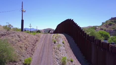 rising aerial over a border patrol vehicle standing guard near the border wall at the us mexico border at nogales arizona