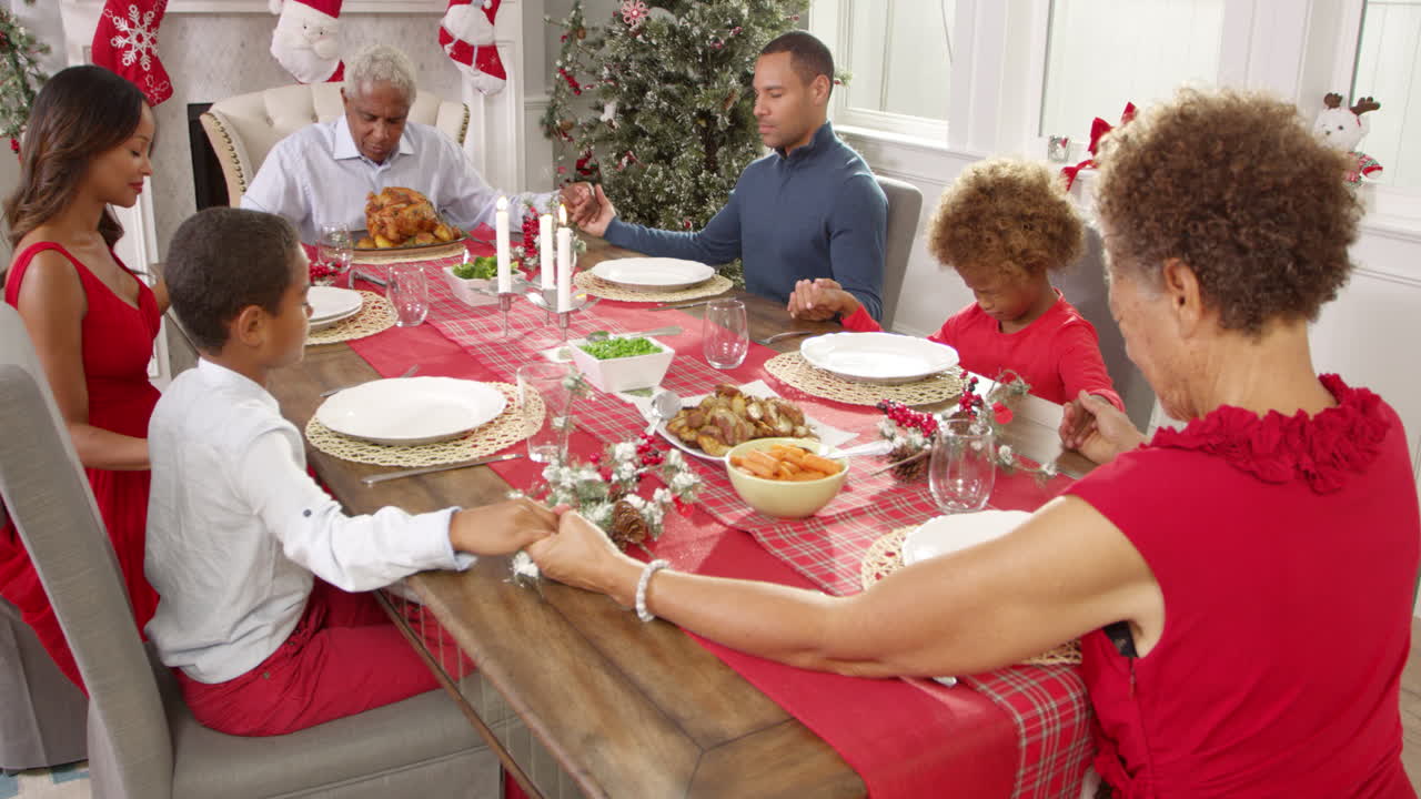 familia diciendo la gracia antes de la comida de navidad filmado en r3d