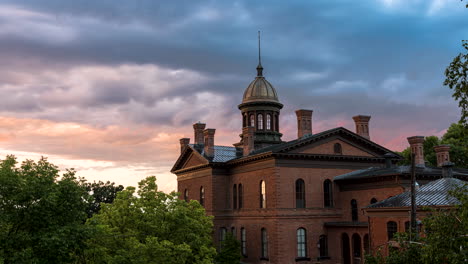 Illuminated-clouds-at-sunset-fly-over-Stillwater-historic-courthouse,-timelapse