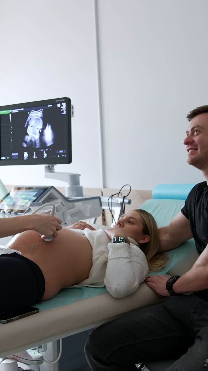 A couple at the obstetrician's office. Pregnant woman having ultrasound check on the future child. Vertical video