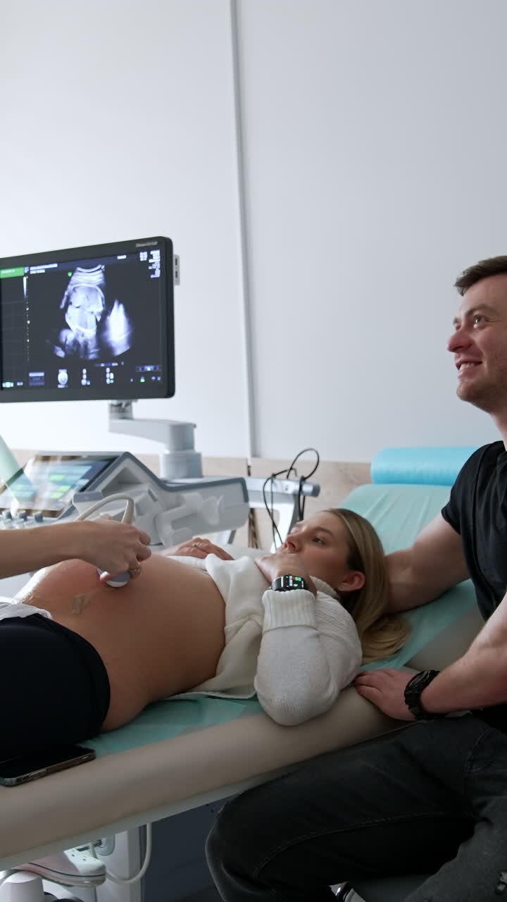 A couple at the obstetrician's office. Pregnant woman having ultrasound check on the future child. Vertical video