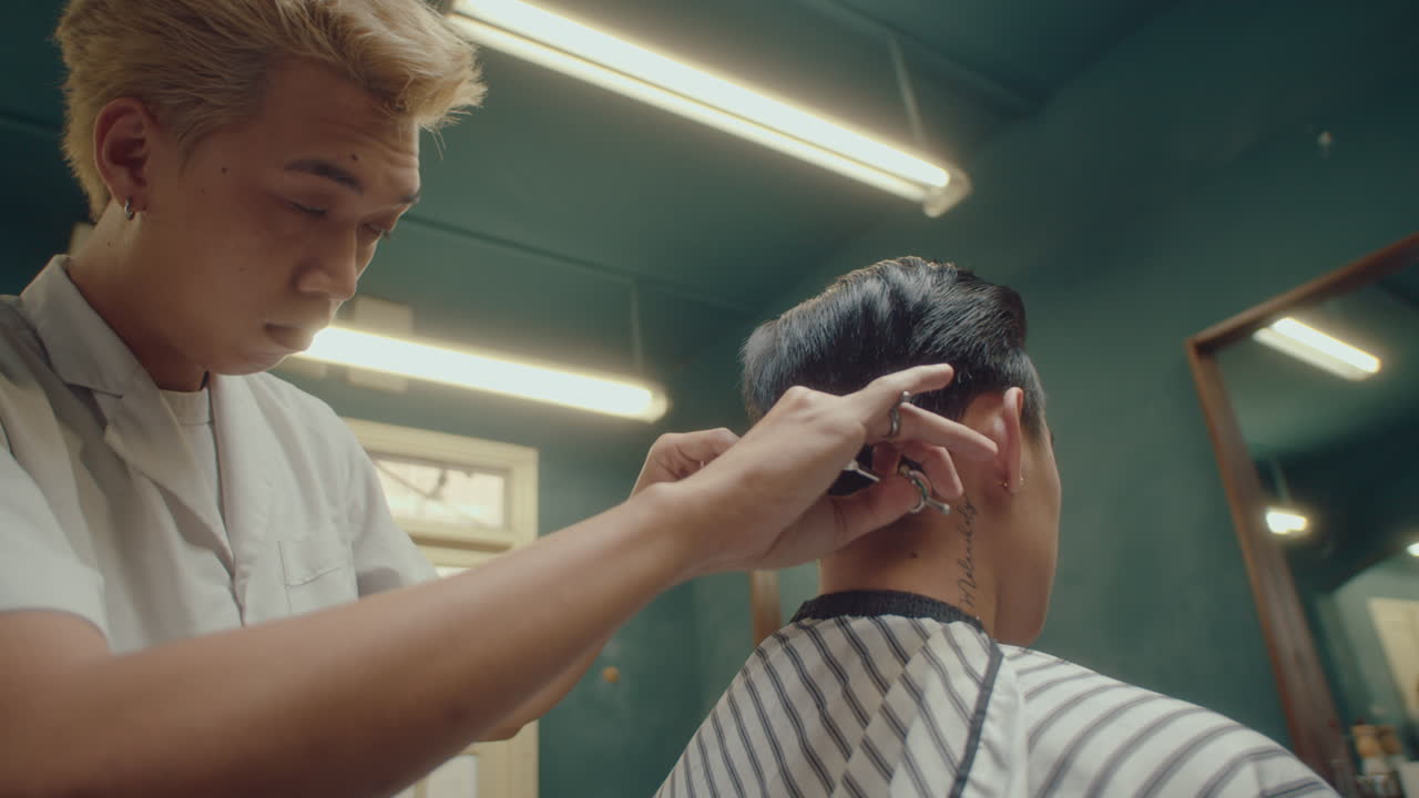 Asian Barber Trimming the Ends of the Hair of Client