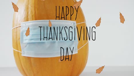Animation-of-happy-thanksgiving-day-text-over-pumpkin-with-face-mask