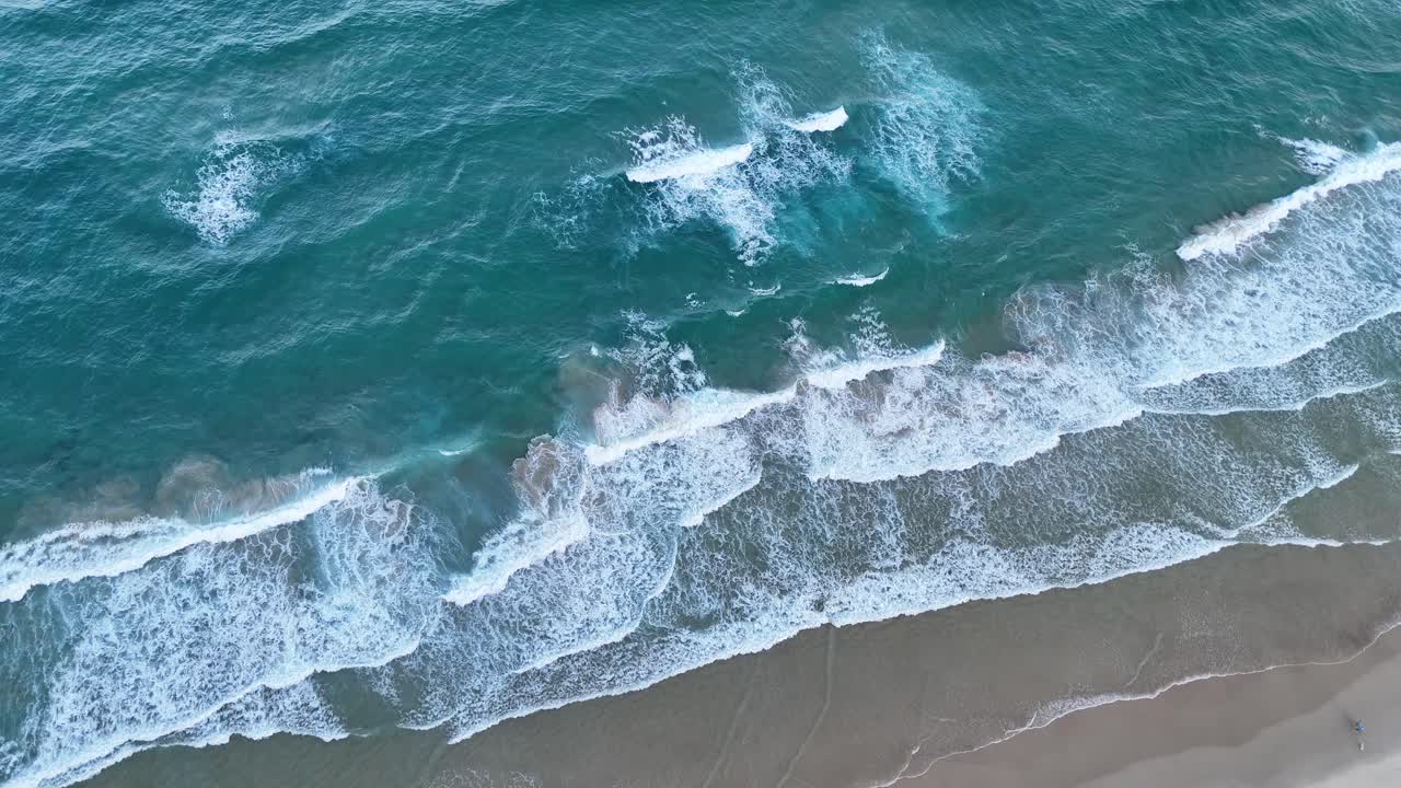 Un drone riprende le onde che si infrangono sulla riva sabbiosa