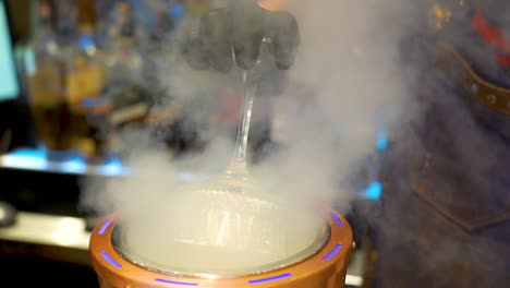 camarero enfriando un vaso con una máquina de hielo en un bar