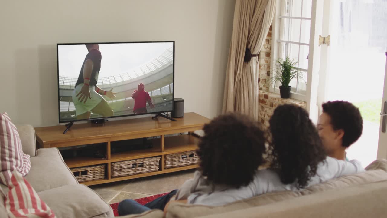 Famiglia felice seduta a casa insieme che guarda una partita di rugby in TV