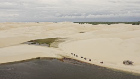 movimiento de grúa de drones del grupo en vehículos todoterreno conduciendo a lo largo de las dunas de arena de brasil