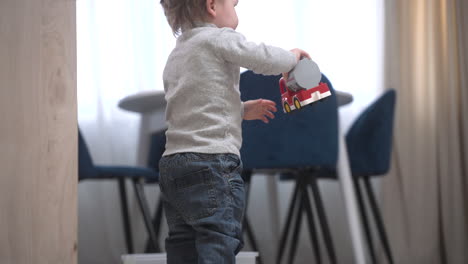 side view of a baby picking up a toy from the top of the dresser