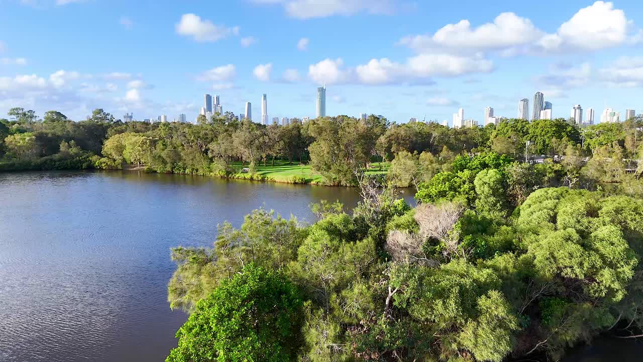 Aerial footage captures Gold Coast's vibrant greenery and skyline under bright daylight, showcasing natural beauty and urban landscape