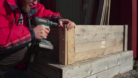 man using an electric screwdriver is doing wood craft