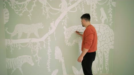 the artist is decorating walls by drawings in the children's room. art painting of the walls in the new house. repair works.