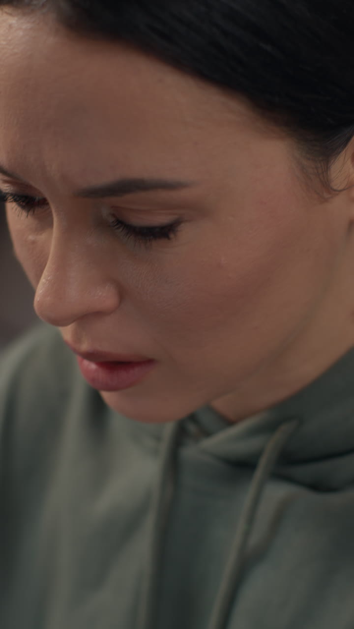 video verticale di primo piano sul viso di una donna ansiosa seduta in casa sul divano che lavora da casa usando un portatile preoccupata per la crisi del costo della vita 1