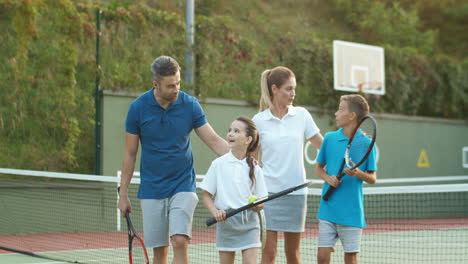 Glückliche-Familie,-Die-Gemeinsam-Den-Platz-Verlässt,-Nachdem-Sie-An-Einem-Sommertag-Tennis-Gespielt-Hat-1