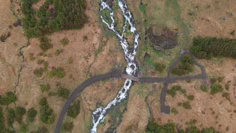 aerial video going straight over the river flowing from the tall and wonderful waterfall bjarnarfoss in the western part of iceland with the lush bush landscape around it