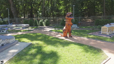dinosaur costume in a park with miniature buildings